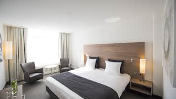 Une chambre d’hôtel avec un grand lit, une chaise, une petite table et une lampe.