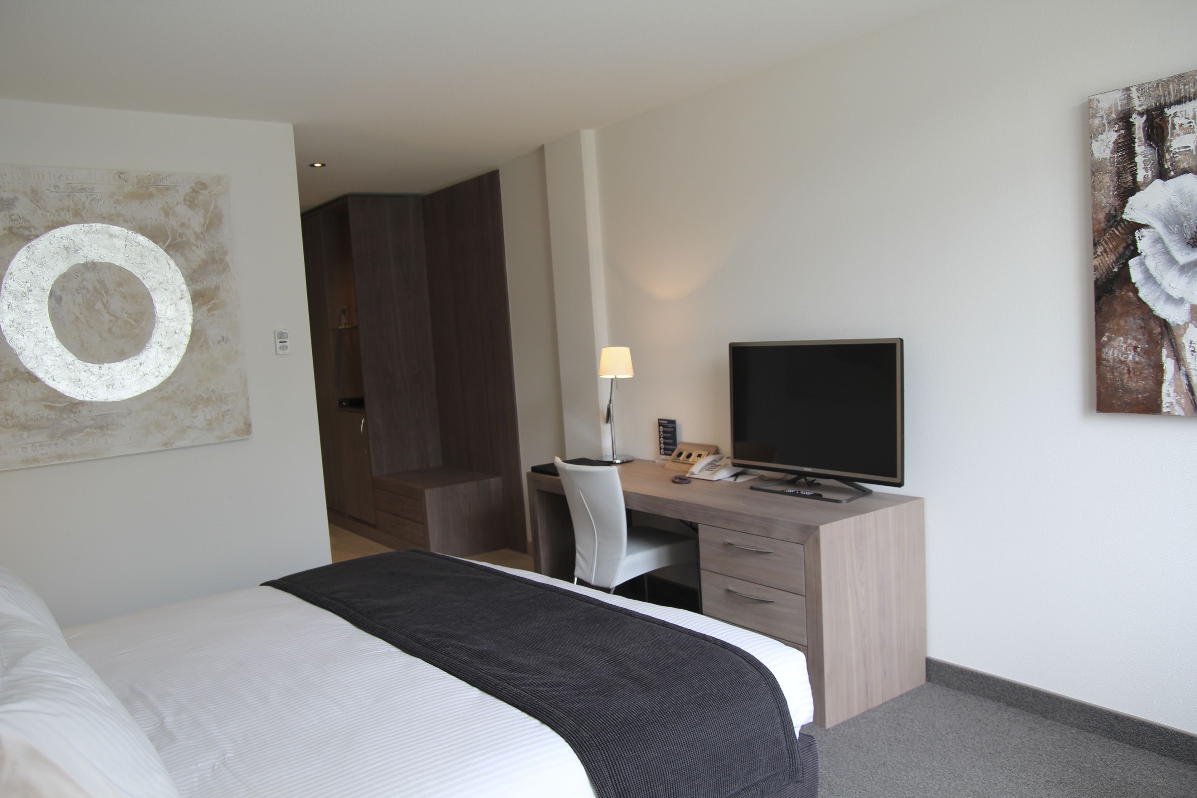A hotel room with a bed, a desk with a computer, and a television.