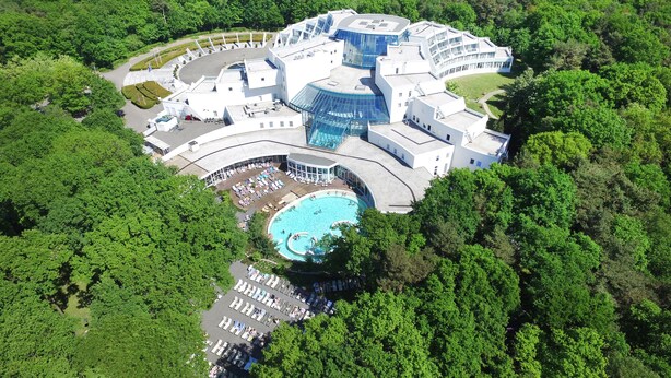 An aerial view of a resort with a swimming pool, multiple buildings, and lush greenery surrounding it.