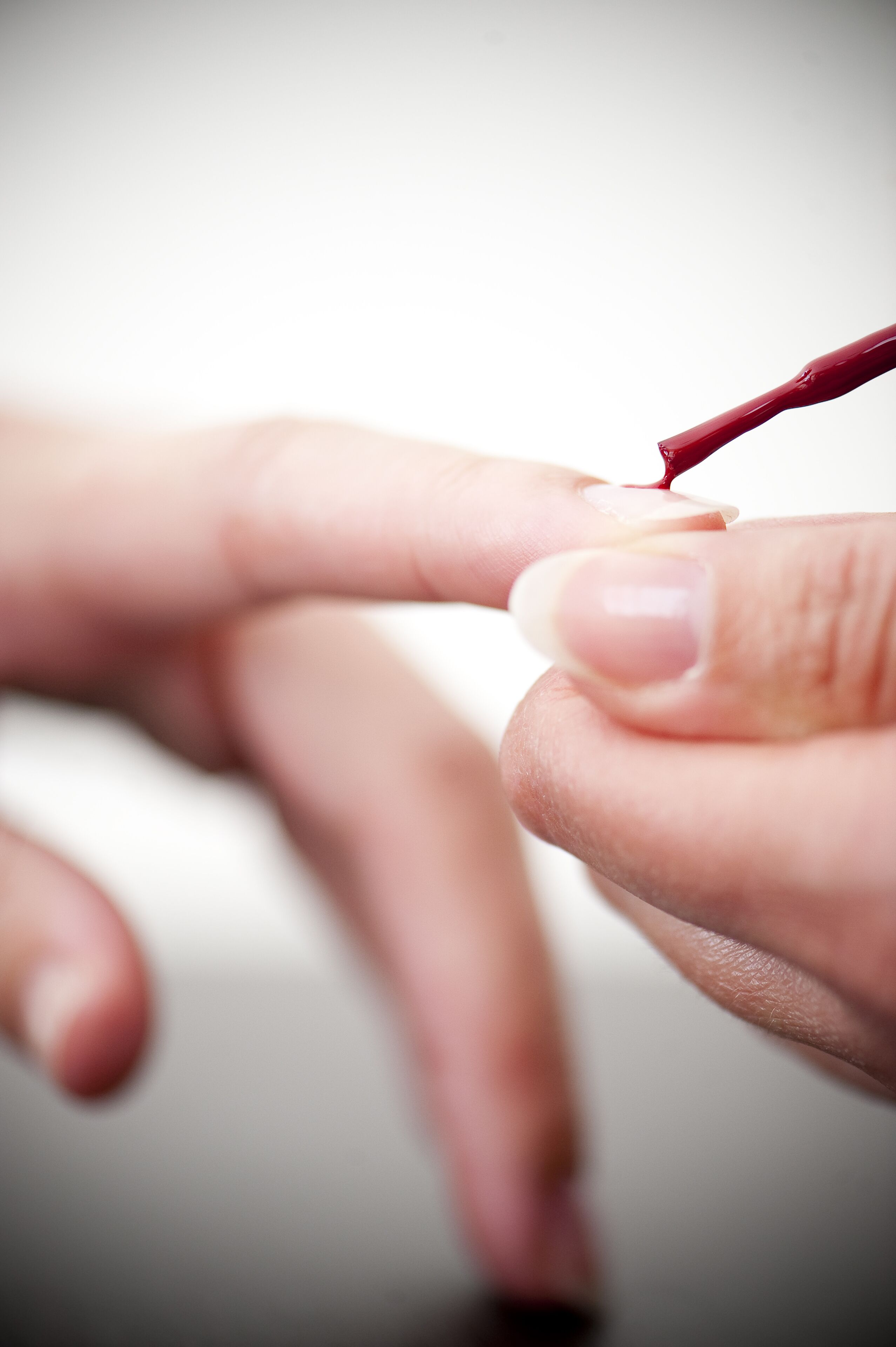 Een detailopname van een hand die een rood voorwerp vasthoudt, mogelijk een pen of gereedschap, in de buurt van een vinger.