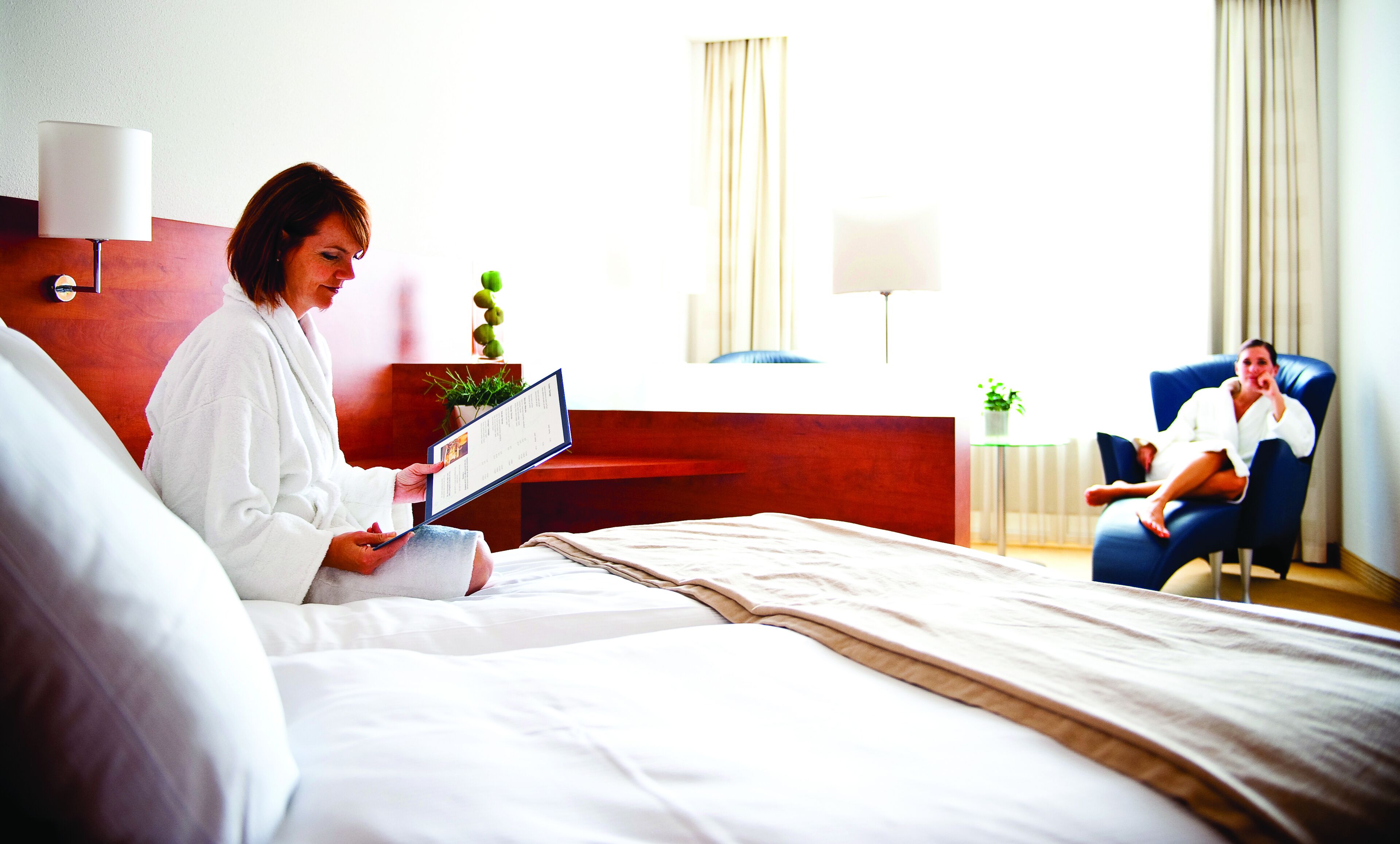 A hotel room with a bed, a desk, and a chair.