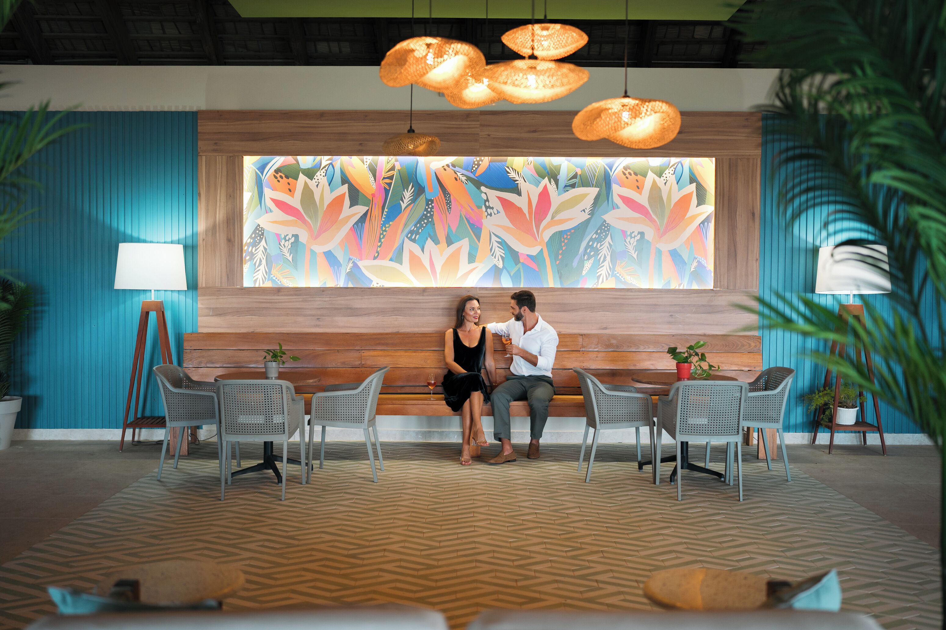 A reception area with a wooden bench, two chairs, a table, and a colorful wall mural.