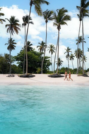 A beach with palm trees and clear turquoise water. - Wyndham Alltra Samana All-Inclusive Resort (Las Galeras)