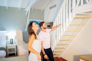 A couple standing on a staircase with a modern interior design, including a white railing and a minimalist aesthetic. - Wyndham Alltra Samana All-Inclusive Resort (Las Galeras)