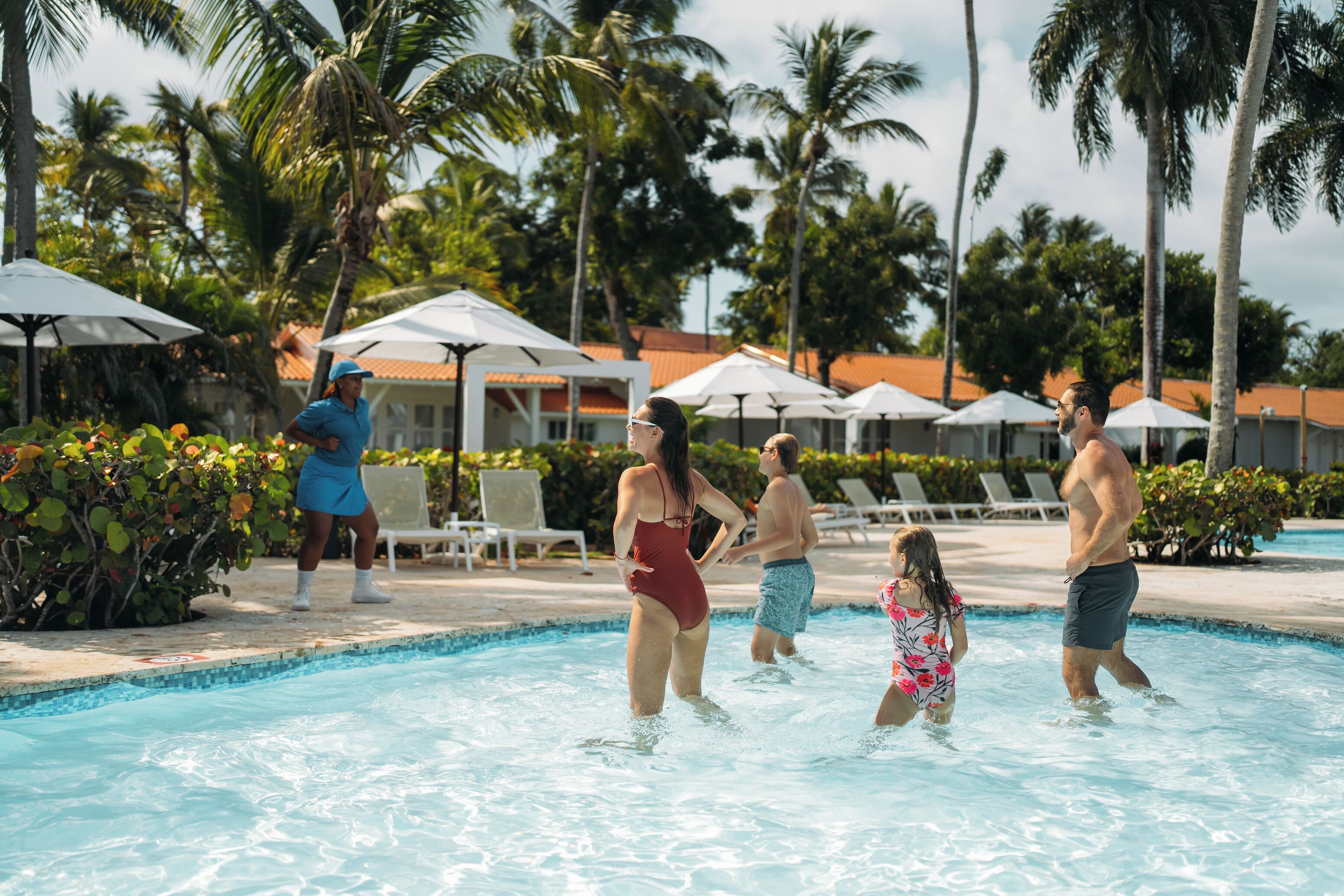 A swimming pool area with palm trees and umbrellas.