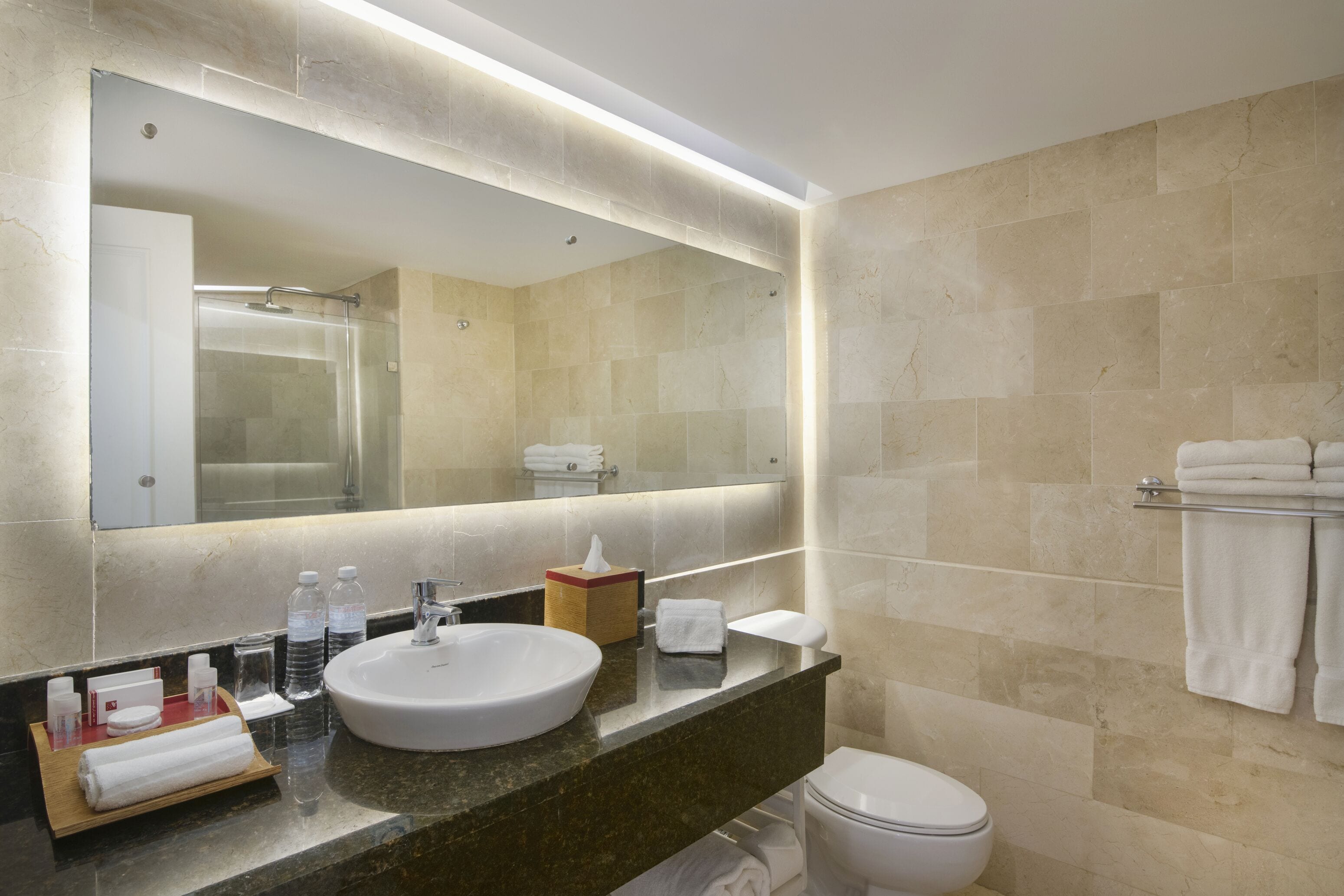 A modern bathroom with a large mirror, a sink, and a toilet.