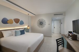 Habitación de hotel con una cama, un escritorio, una silla, un reloj de pared y una televisión.