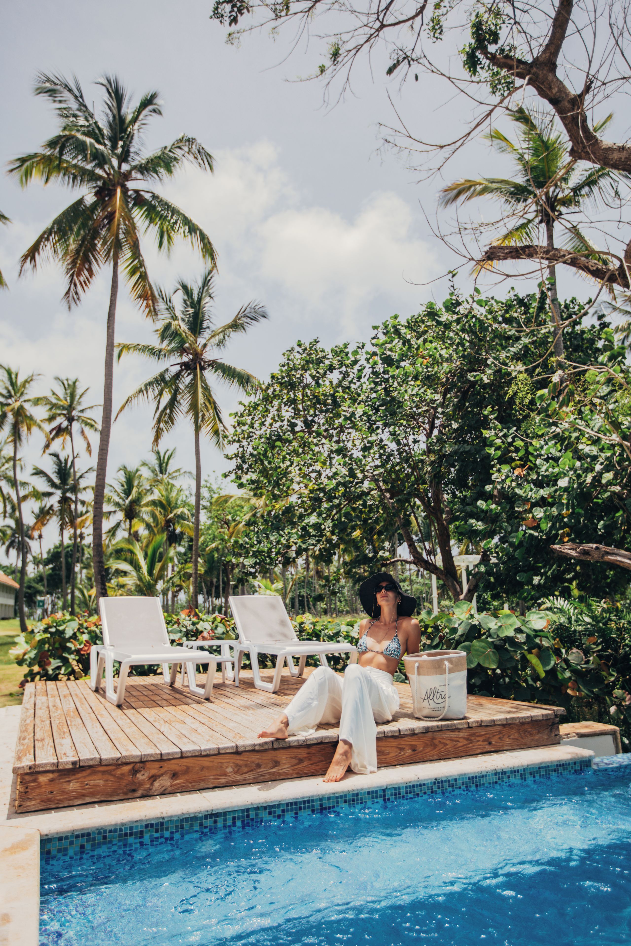 Un espace aménagé au bord de la piscine, avec des chaises longues, une terrasse en bois et une vue dégagée sur la piscine.