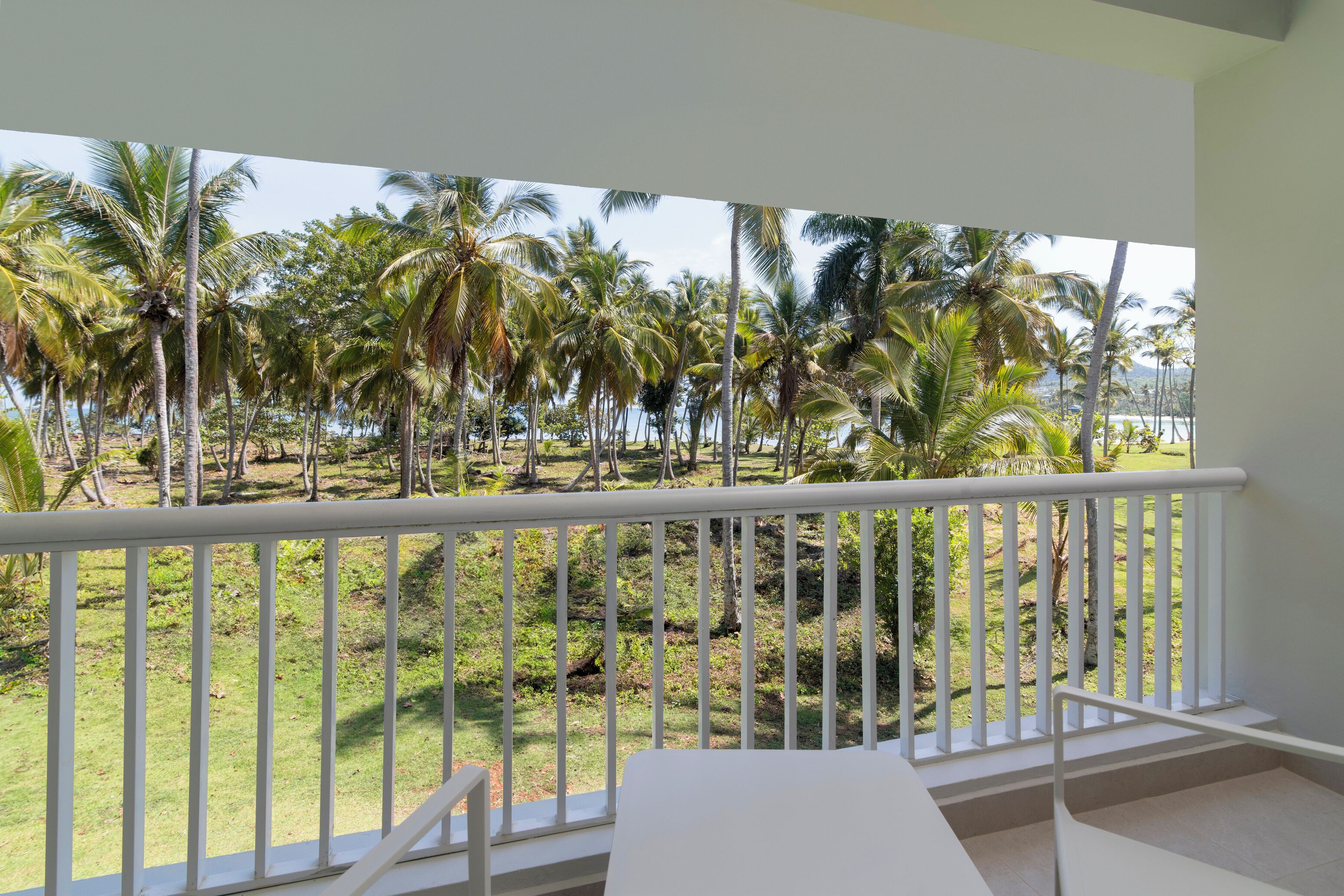 Un balcon avec une balustrade blanche, une table blanche et des chaises.
