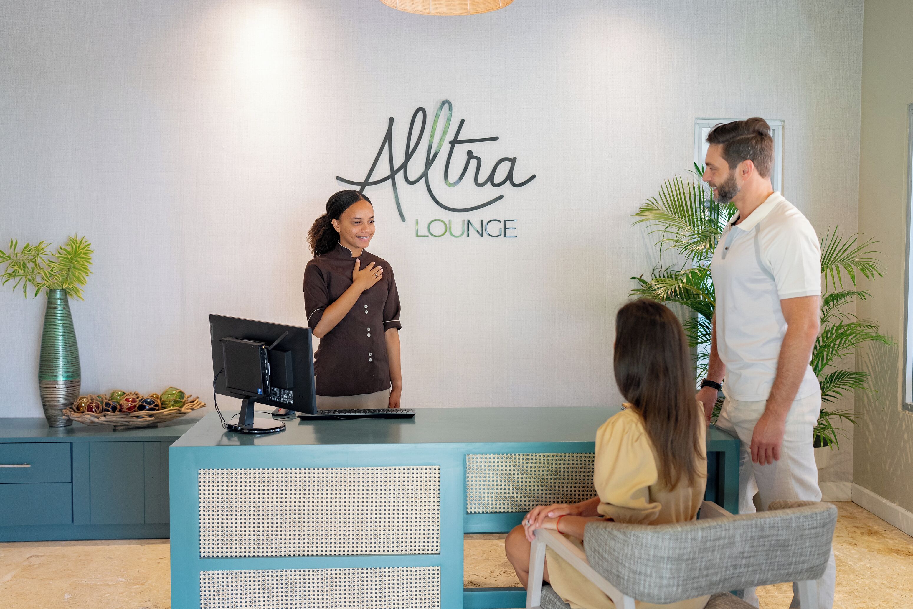 Un espace d’accueil avec une enseigne indiquant « Altra Lounge », un comptoir de réception, un ordinateur et des sièges pour les clients.