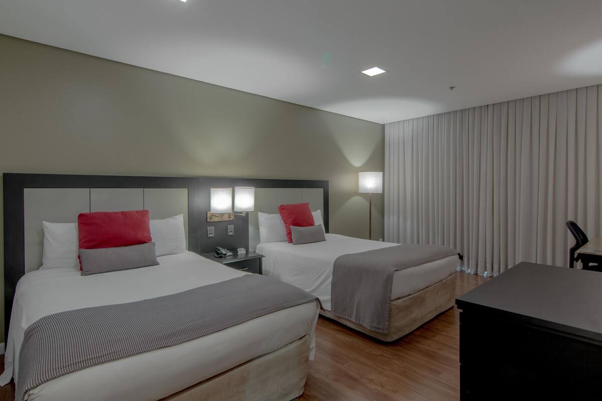 Een hotelkamer met twee bedden, een bureau en een stoel.