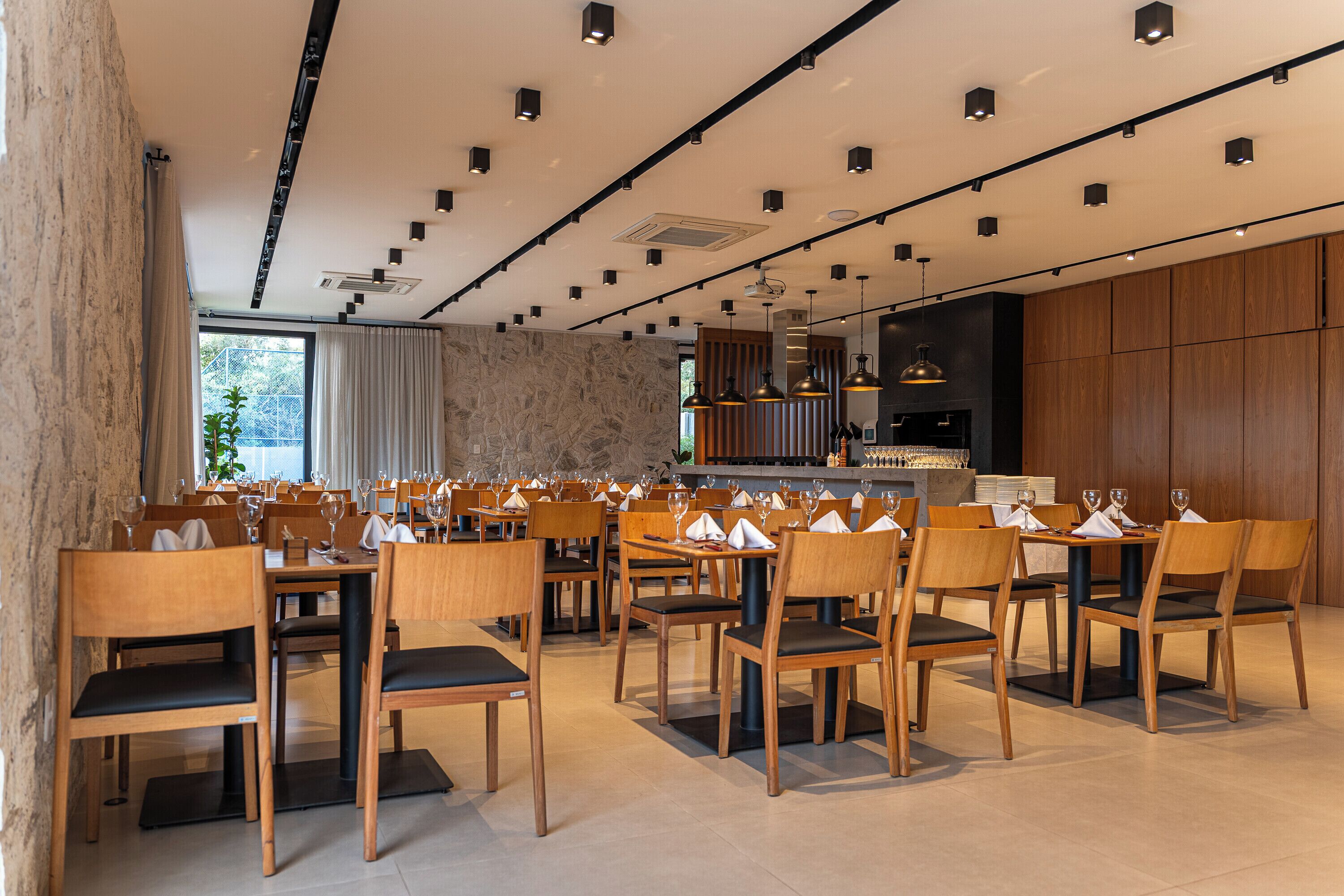 A restaurant with multiple tables and chairs, a bar area, and a stone wall.