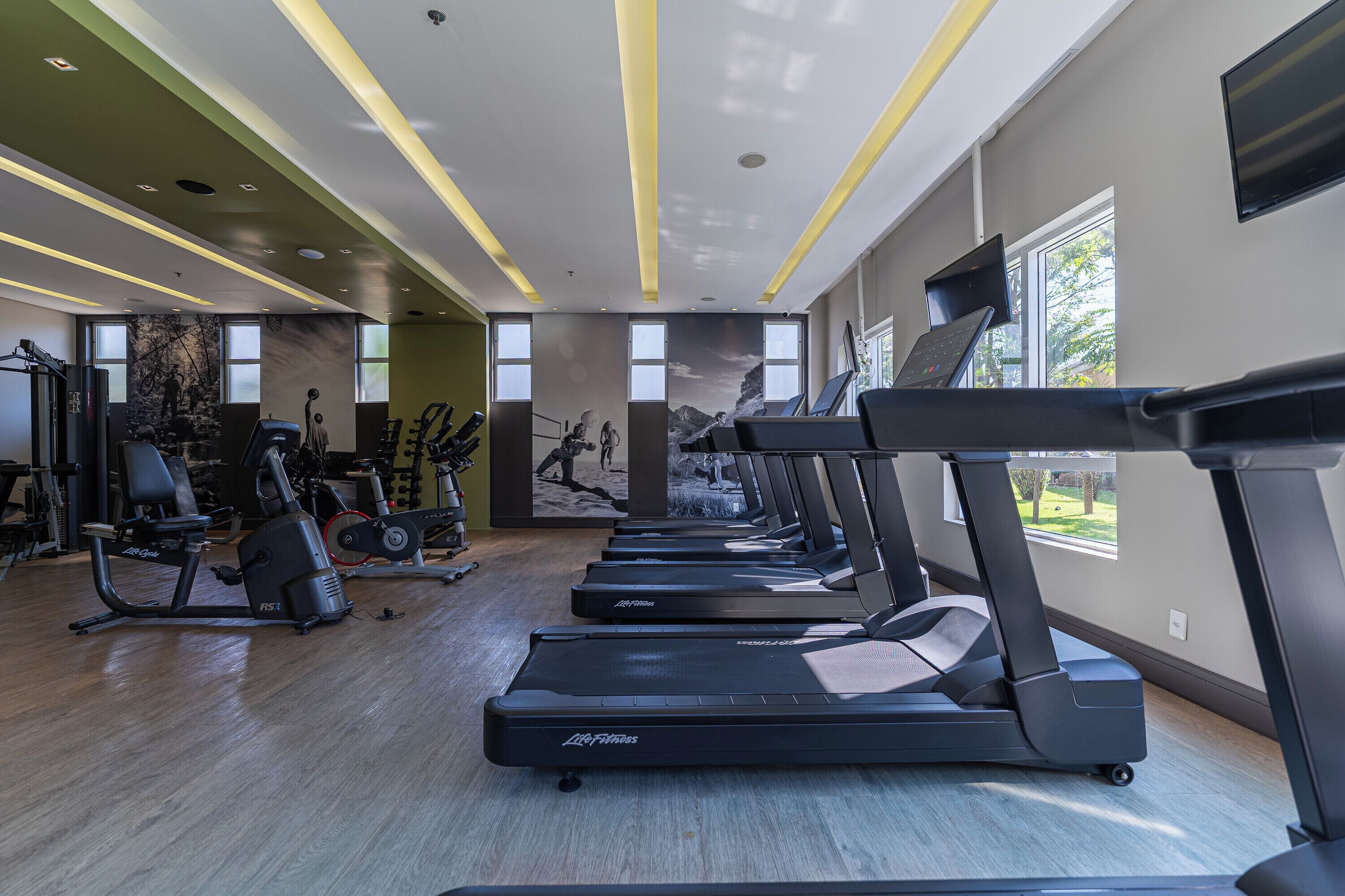 Un gimnasio con cintas de correr, bicicletas estáticas y máquinas de pesas.