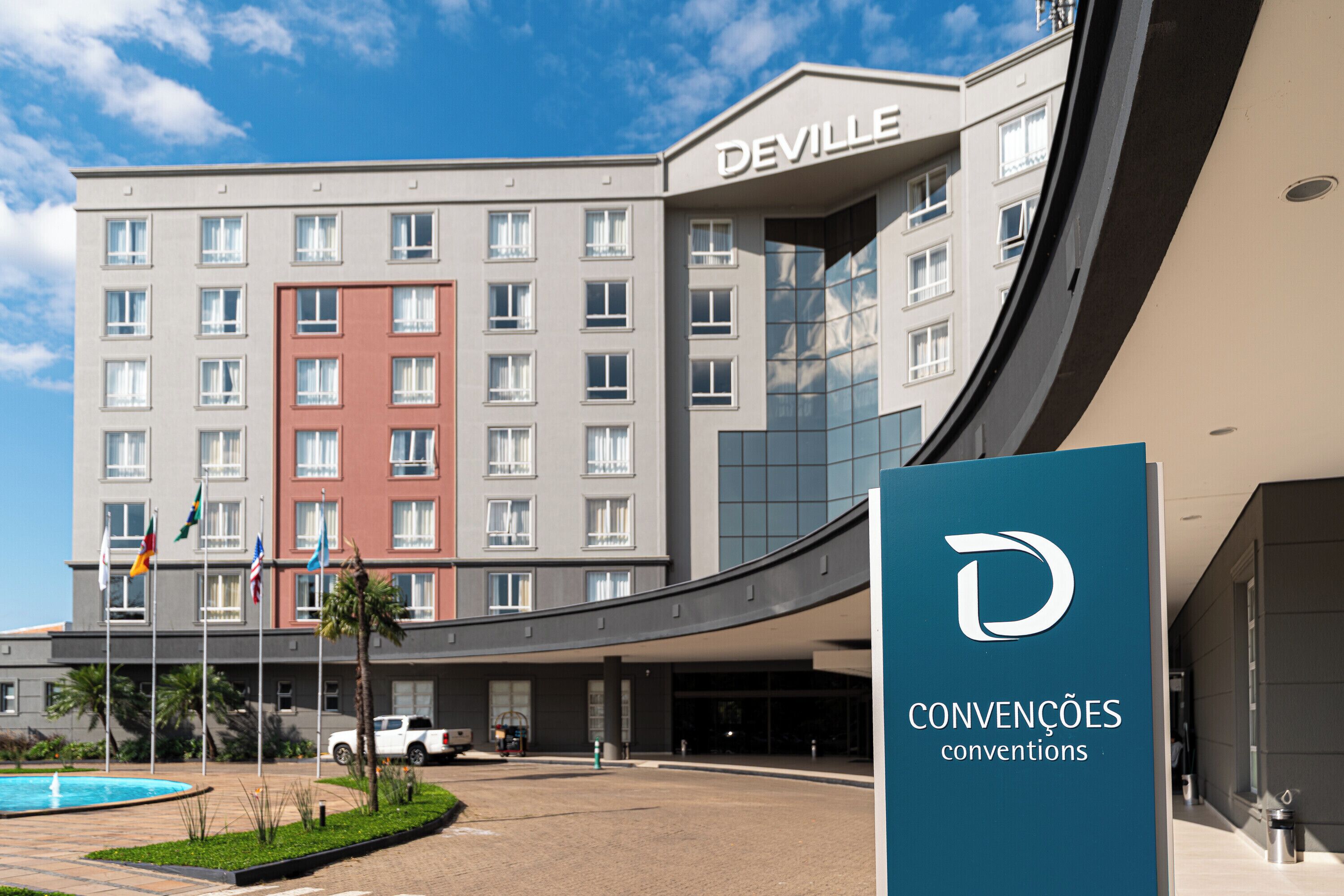 Um hotel com design moderno, exibindo um destaque para o letreiro 'DEVILLE' na fachada.