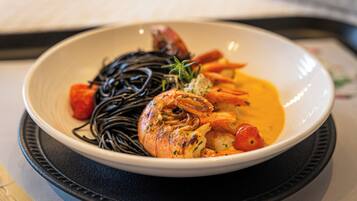 Un bol de nourriture contenant des crevettes, des légumes et des nouilles, le tout servi sur une assiette.