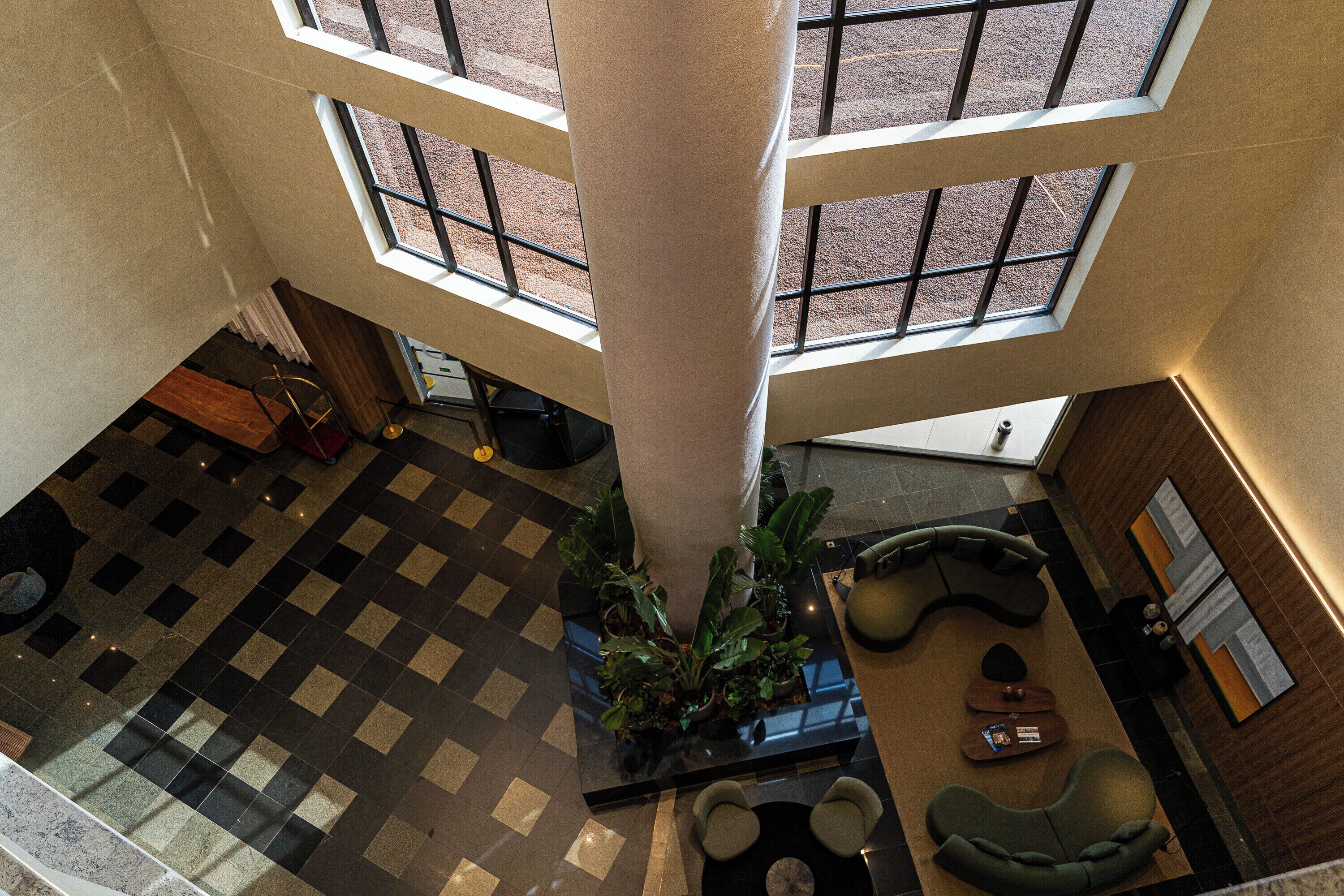 A lobby with a checkered floor, a central column, and a seating area with a sofa and chairs.