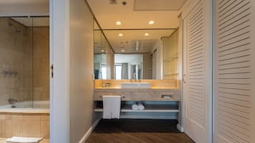 Een moderne badkamer met een douchecabine van glas, een wastafelmeubel en een inloopkast met schuifdeuren.