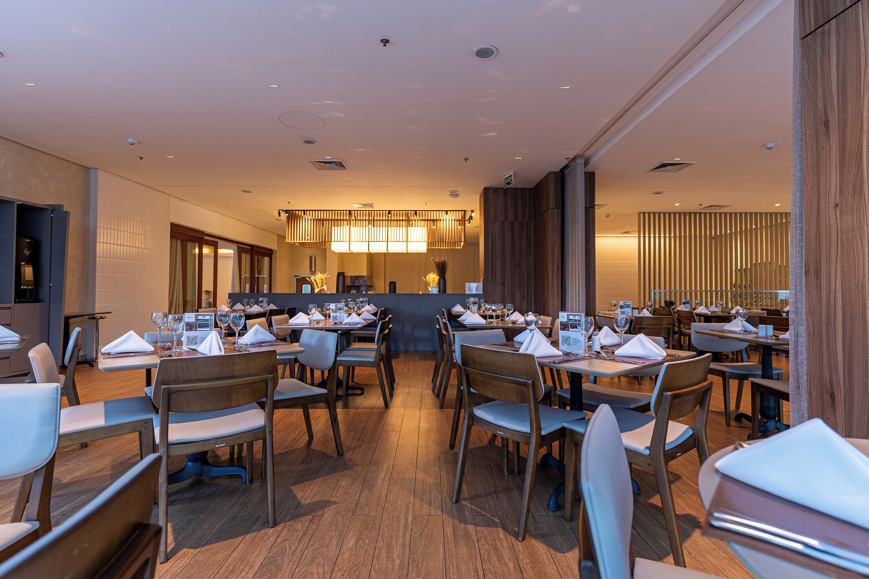 Un interior de restaurante moderno con suelo de madera, varias mesas y sillas.