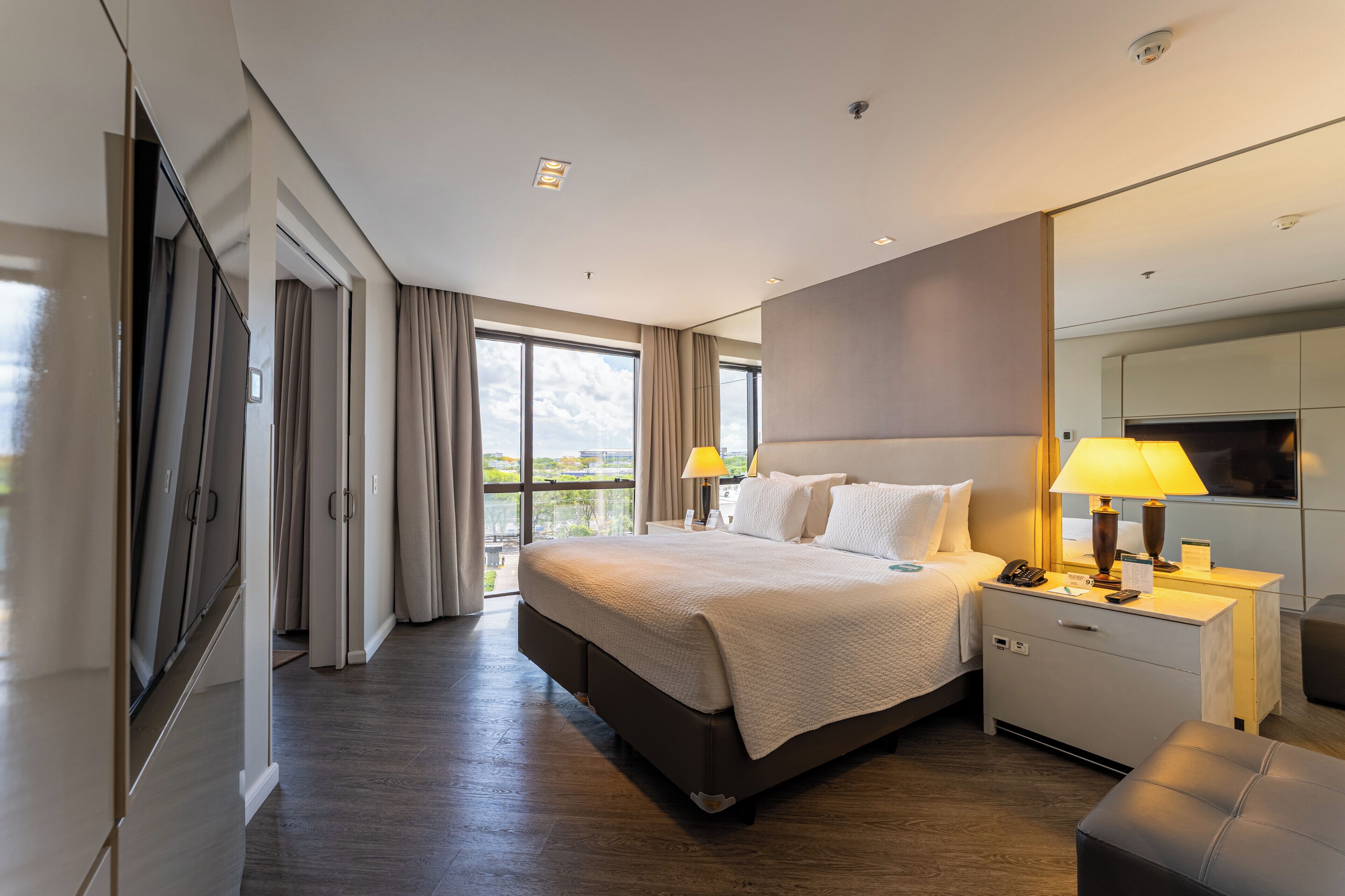 Une chambre d’hôtel avec un grand lit, des lampes de chevet, un bureau avec un téléphone et une vue sur l’extérieur.