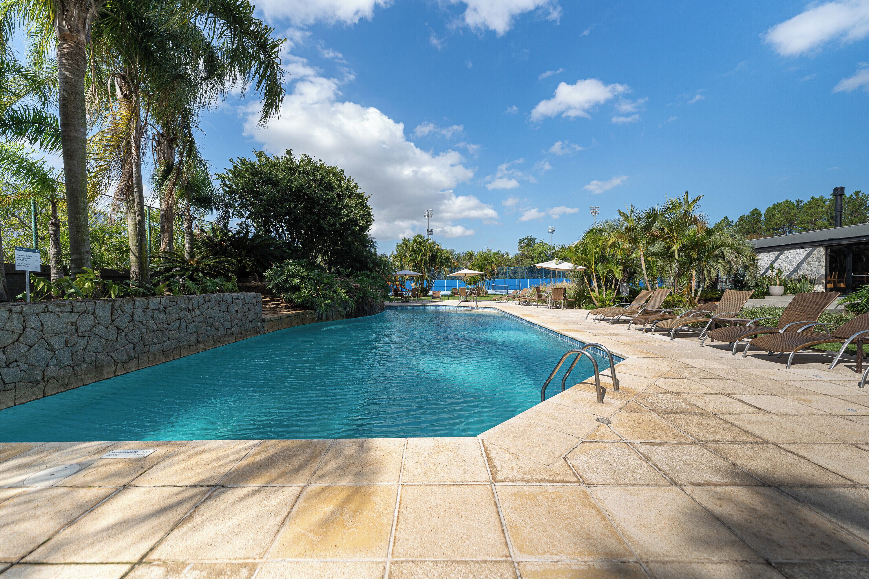 Piscina com muro de pedra e espreguiçadeiras.