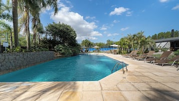 Piscina com muro de pedra e espreguiçadeiras.