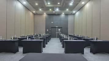 A conference room with rows of tables and chairs, equipped with water bottles and nameplates.