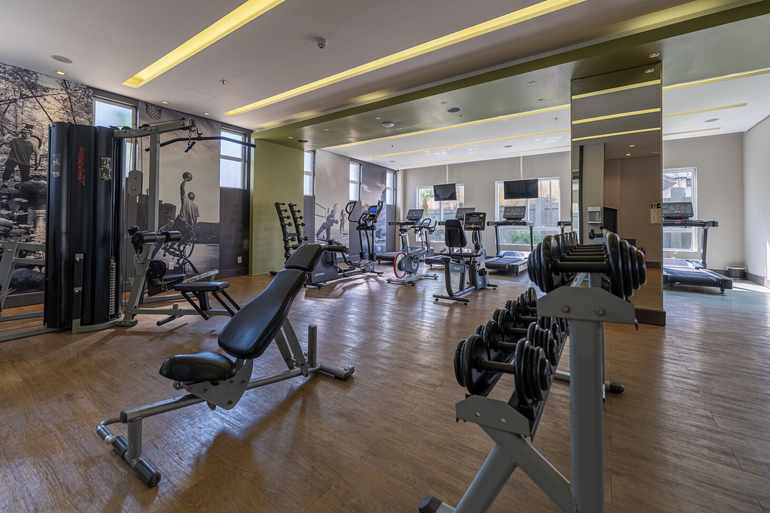 Uma academia com diversos equipamentos de exercício, incluindo esteiras, bicicletas ergométricas e aparelhos de musculação.