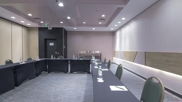 A conference room with a long table, chairs, water bottles, and a projector screen.