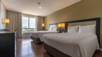 Quarto de hotel com duas camas, uma escrivaninha e vista para a cidade.
