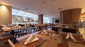 A spacious restaurant with multiple dining tables, chairs, and a large window providing a view of the outdoors.