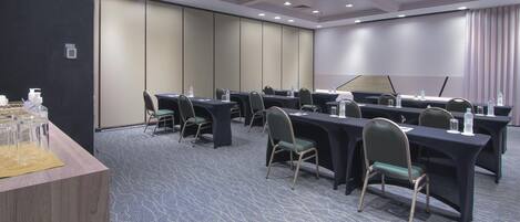 Un salón de conferencias con varias mesas y sillas, equipado con botellas de agua y tarjetas de identificación.