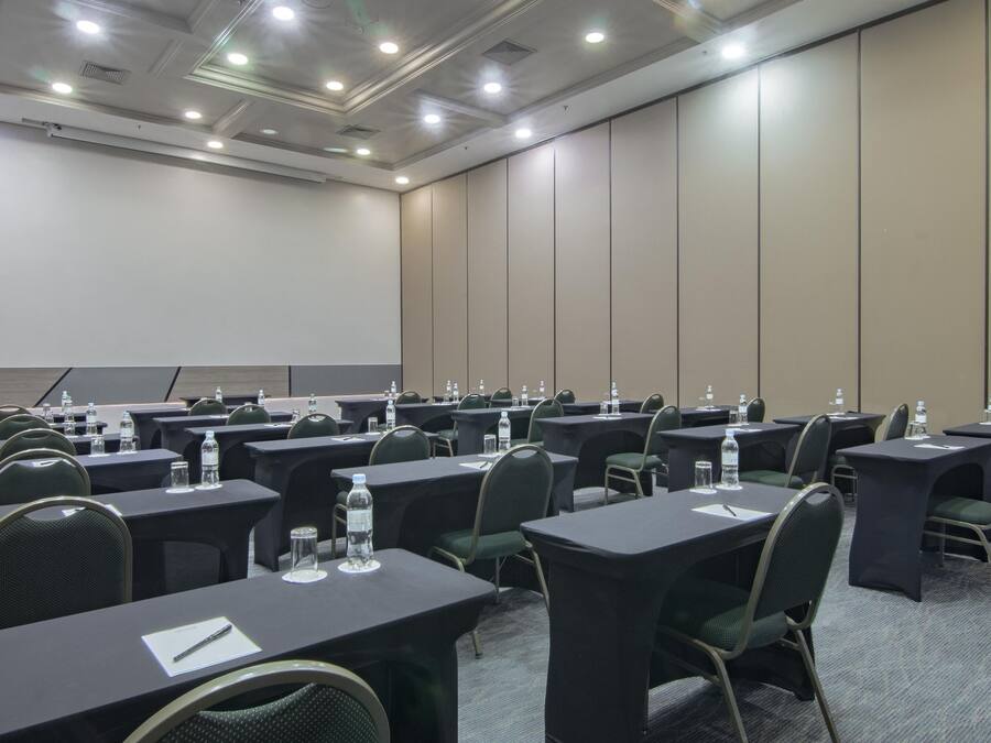 A conference room with multiple tables and chairs, equipped with water bottles and notepads.