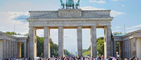 A large historical monument with columns and a statue on top, surrounded by a crowd of people.