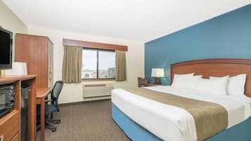 Habitación de hotel con cama, escritorio, silla, televisor y ventana.