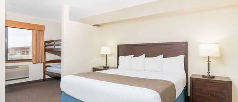 A hotel room with a large bed, two bedside tables with lamps, a window with curtains, and a view of the outside.
