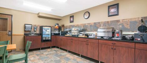 A hotel kitchen with a coffee station, a clock, and a clock with a cappuccino sign.
