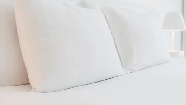 Un lit avec une literie et des oreillers blancs.