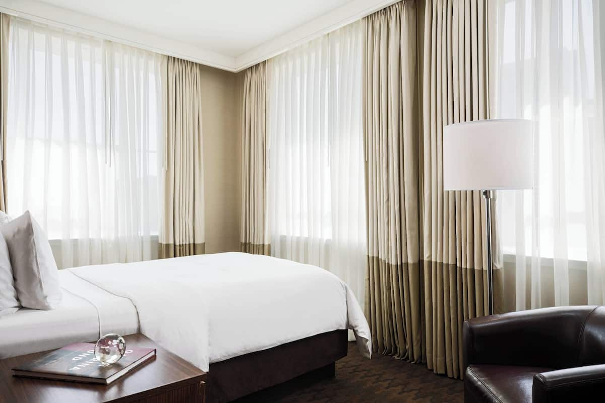 Een hotelkamer met een groot bed, een bank, een lamp en gordijnen.