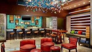 Zona de bar con sillas de cuero rojo, una barra de madera y una variedad de botellas.