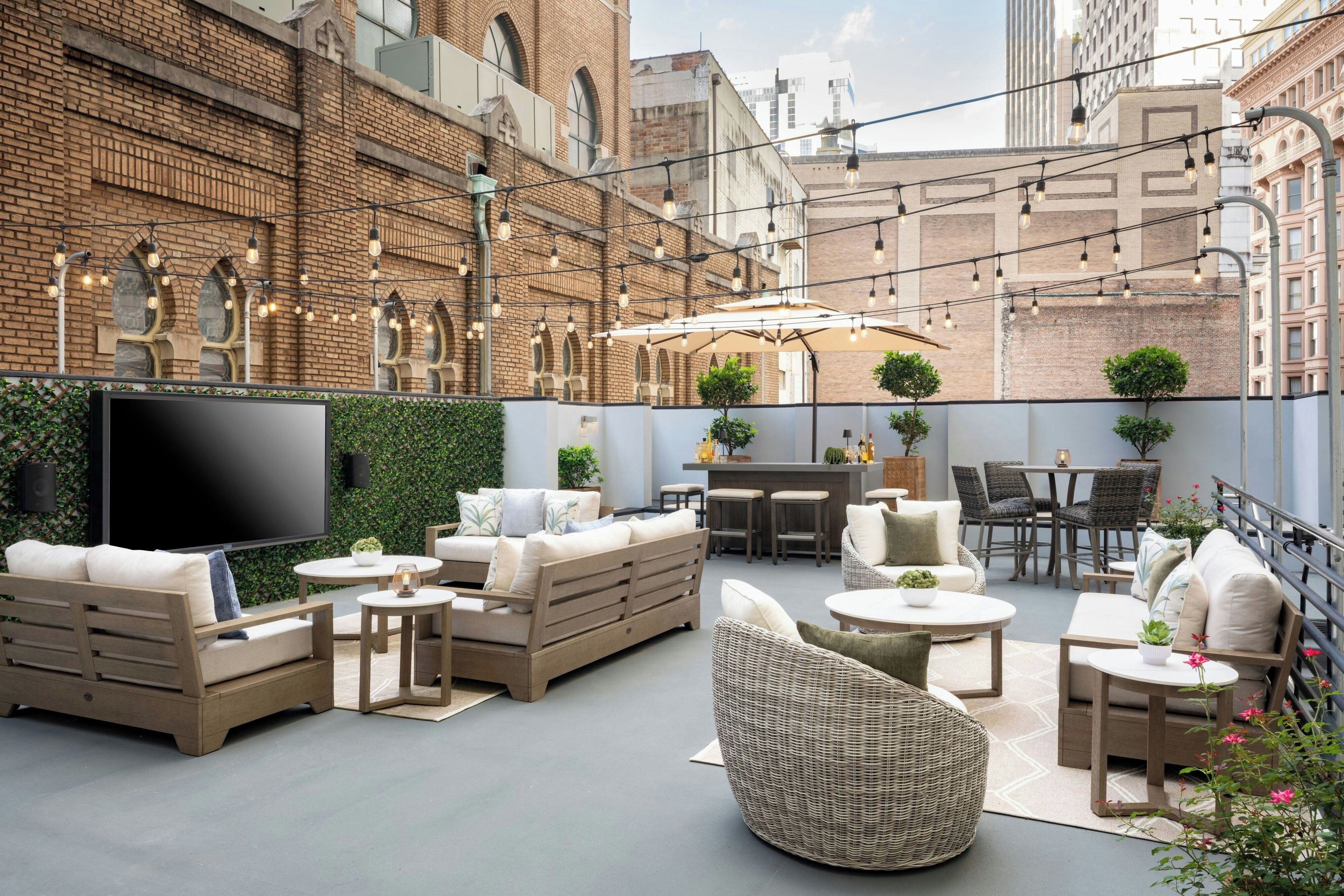 An outdoor patio area with seating, a flat-screen TV, and string lights.