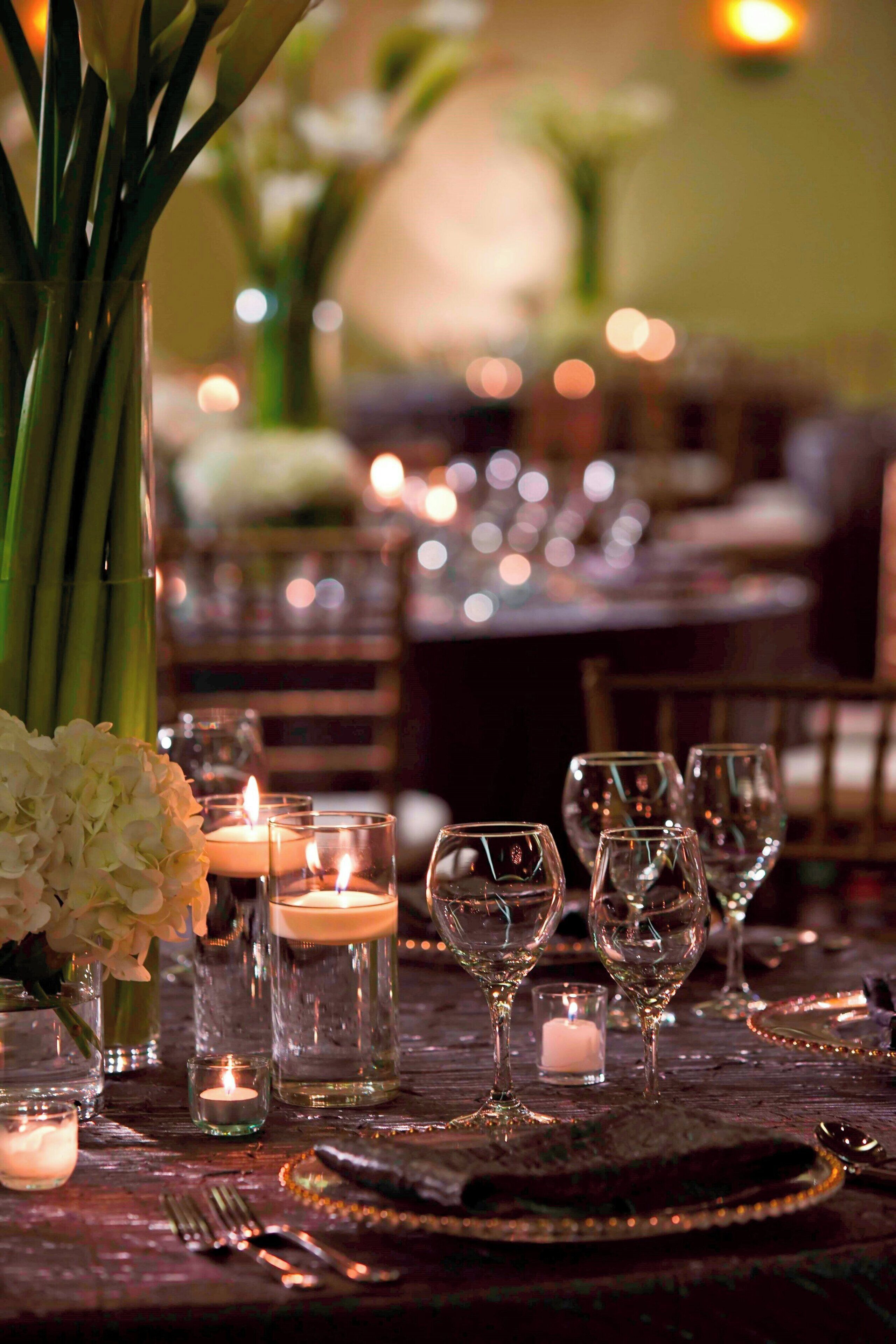 A table set for dining with candles, glasses, and a vase of flowers.