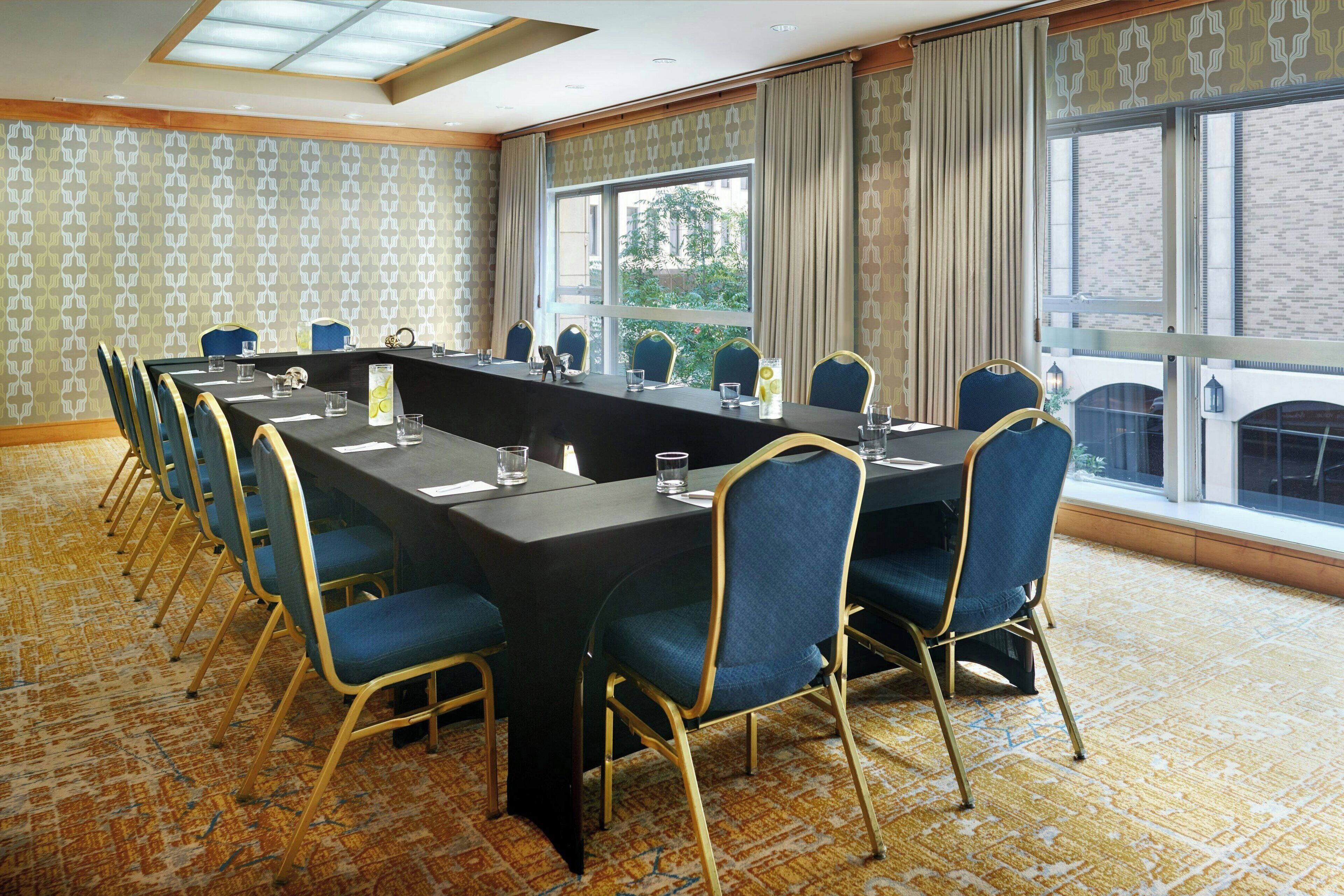 A conference room with a long table, blue chairs, and a carpeted floor.