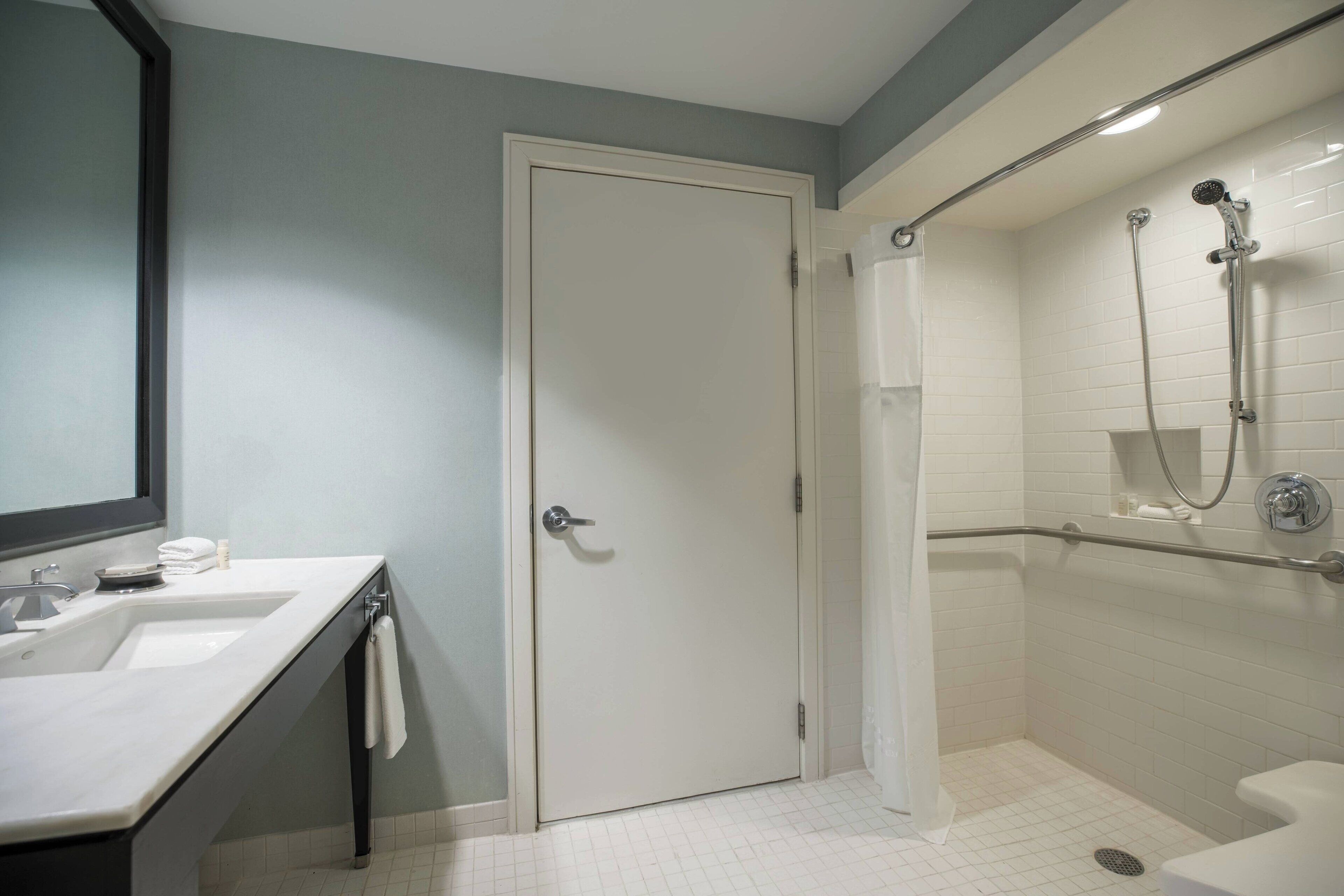 Un baño con lavamanos blanco, espejo y ducha.