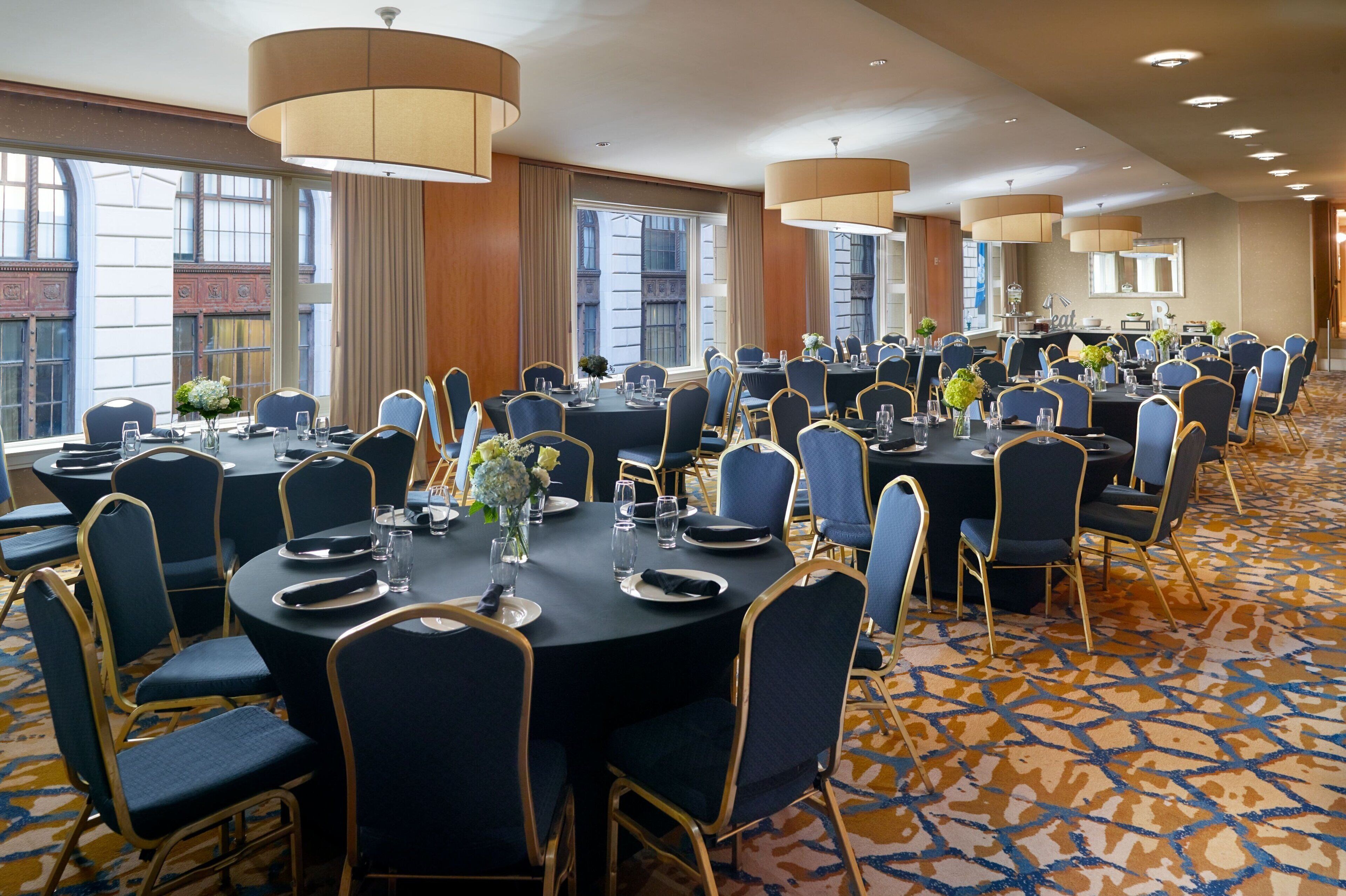 A large conference room with round tables, blue chairs, and beige accents.