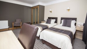 Una habitación de hotel con dos camas, una silla, una mesa y un espejo.