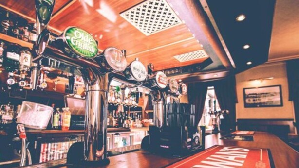 Un bar con múltiples grifos, techo de madera y alfombra roja con el texto 'ACEWARS'.