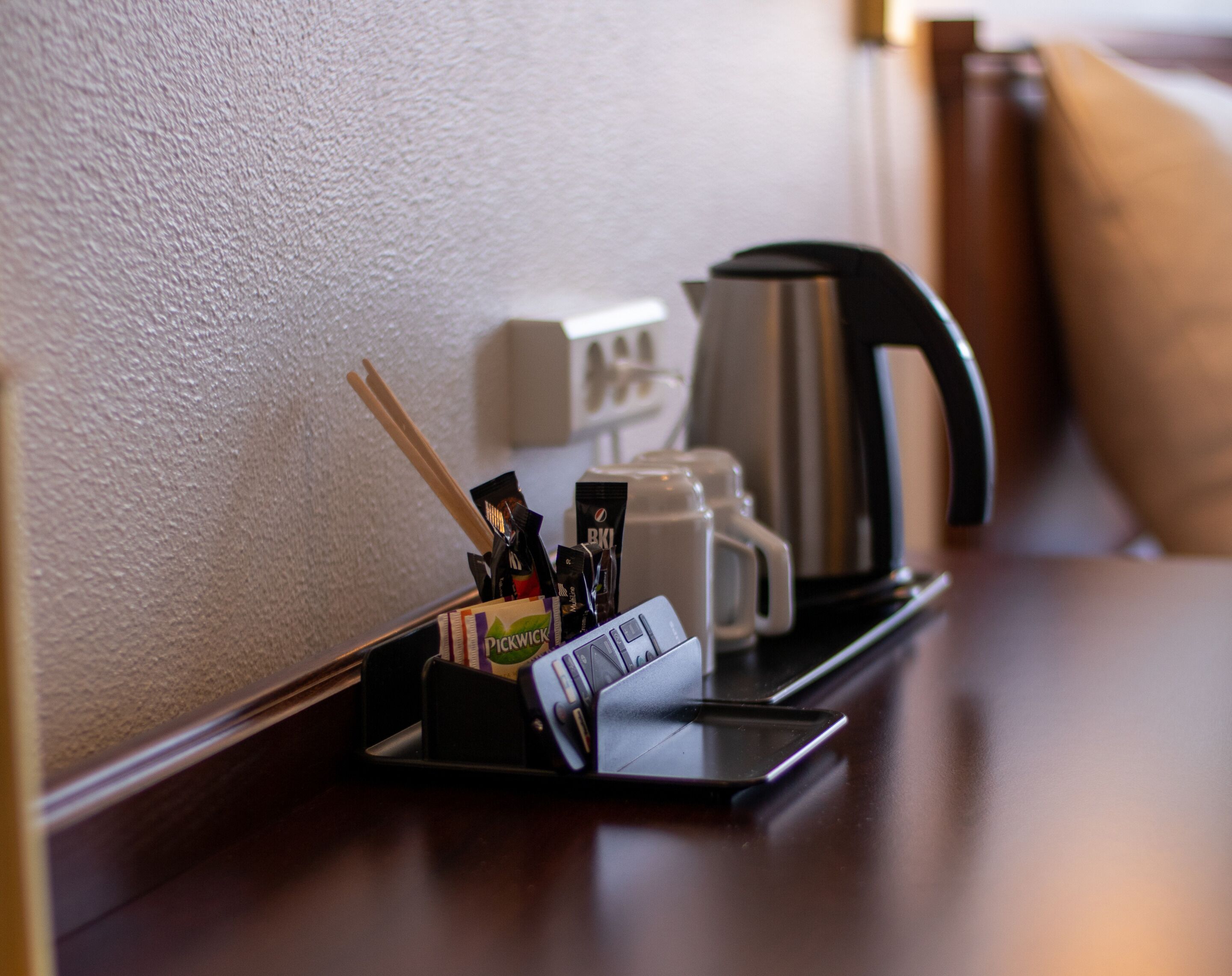 Une table d’appoint dans une chambre d’hôtel, sur laquelle se trouve un plateau noir avec un smartphone, un paquet de cigarettes et un tube de dentifrice.