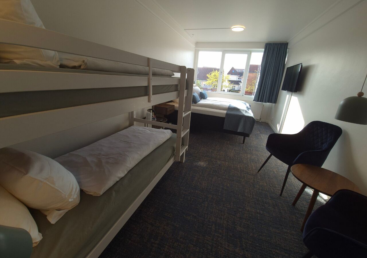 Ein Zimmer mit Etagenbetten, einem Schreibtisch, einem Stuhl und einem Fernseher.