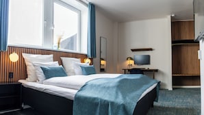 Una habitación de hotel moderna con cama, mesitas de noche, televisor y escritorio.