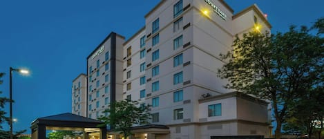 Un hotel de varios pisos con un llamativo letrero de 'Courtyard by Marriott', una entrada cubierta y una fachada bien iluminada.